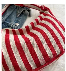Detail view of red and beige striped canvas fabric texture on a half-moon shoulder bag