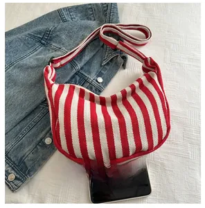 Detailed canvas texture of a red and white striped crescent bag with a wide strap