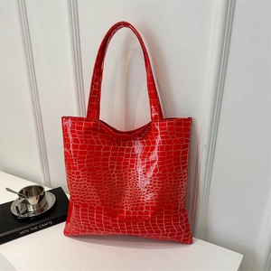 Large red crocodile pattern tote bag with glossy finish and double handles in city setting