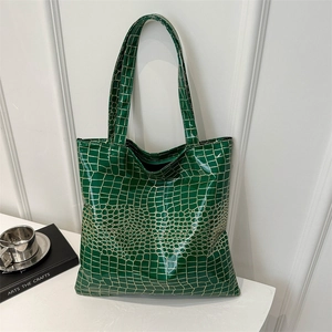 Glossy dark green crocodile embossed large tote bag for women shown on a white table