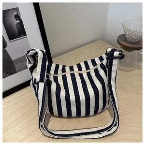 Detailed shot of striped canvas handbag with thick adjustable strap on wooden table