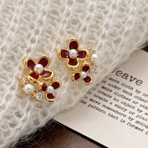 Détail de boucles d'oreilles dorées asymétriques avec fleurs émaillées et perles