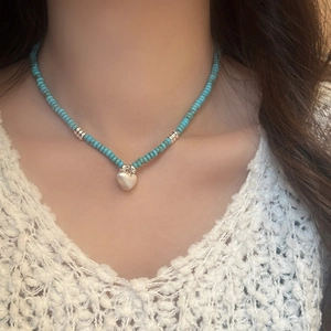 Handmade turquoise bead necklace featuring a brushed silver-tone heart pendant on a model