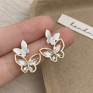 Close-up of elegant double butterfly earrings with marquise-cut zircons on a hand