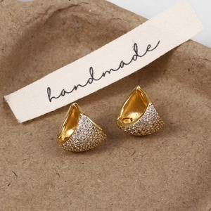 Macro shot of gold-plated earrings with pave-set zircon crystals on a handmade card