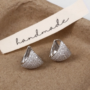 Detail of silver drop earrings with micro-pave cubic zirconia on handmade cotton background