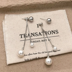 Detail of silver tassel earrings with champagne pearls and long snake bone chains