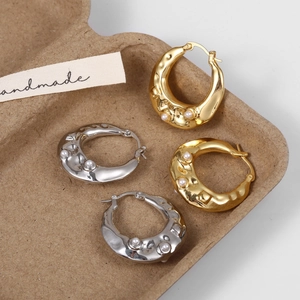 Close-up of chunky French vintage gold and silver pearl earrings with lava metal texture
