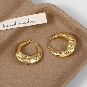 Close-up of vintage gold earrings with textured surface and embedded white pearls