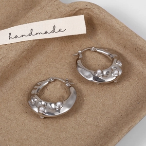 Detailed macro view of silver lava-textured hoop earrings with small pearl inlays
