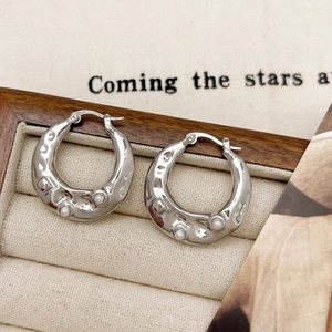 Macro shot of silver irregular texture earrings with pearl accents in a jewelry box