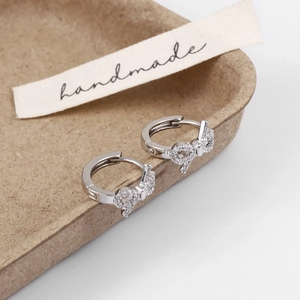 Macro shot of silver bow earrings with zircon stones on handmade label base