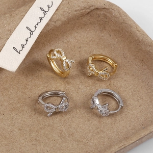 Detailed close-up of bow earrings with micro-set cubic zirconia in gold and silver finish