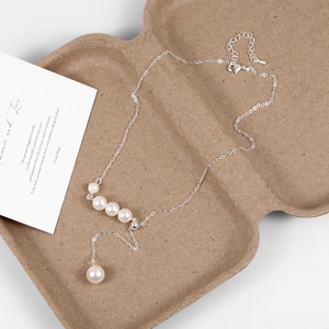Macro shot of silver Y-shaped necklace with five white pearls on a textured background