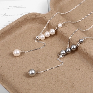 Detail of adjustable Y-shaped pearl necklaces in white and grey silver on a display tray
