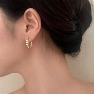 Elegant U-shaped gold horse-shoe earrings featuring three vertical white pearls on model