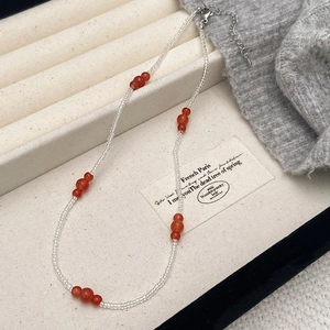 Elegant beaded necklace with red natural stone beads and silver lobster clasp on a tray