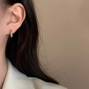 Détail de créoles en argent avec émail bleu clair et petits diamants blancs sur l'oreille