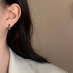 Gros plan de boucles d'oreilles créoles argentées texturées portées par un mannequin