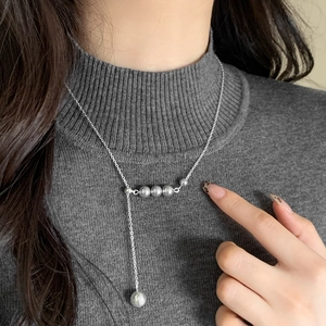 Elegant adjustable Y-shaped necklace with grey pearls on a dark turtleneck sweater