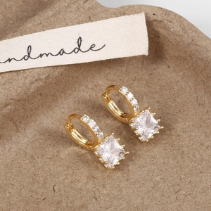 Macro shot of gold zircon drop earrings on a handmade tray showing delicate pavé details