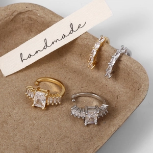 Gros plan de quatre ear cuffs en or et argent avec zircons sur plateau artisanal