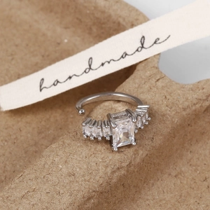 Vue macro d'un earcuff en argent avec zircon rectangulaire sur un plateau artisanal