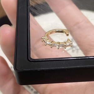 Détail de la bague d'oreille dorée en forme de C avec zircons étincelants dans une boîte
