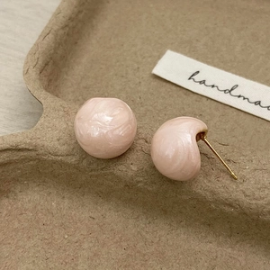 Pink marble resin heart stud earrings with gold metal base on handmade label background
