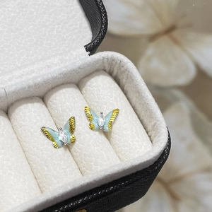 Makroaufnahme von mintgrünen Emaille-Schmetterlingsohrringen mit Goldbeschichtung und Zirkon