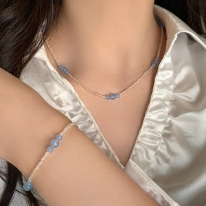 Vintage necklace set with blue natural stones and pink beads on white satin shirt