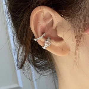 Close-up of silver ear cuffs set with sparkling rectangular zircons on female ear