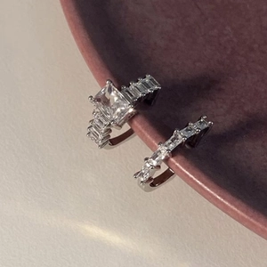 Elegant silver sparkling zircon ring set with emerald cut stone on red ceramic bowl