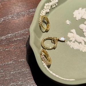 Detailed view of gold plated micro-paved hoop earrings with drop gemstone in ceramic tray