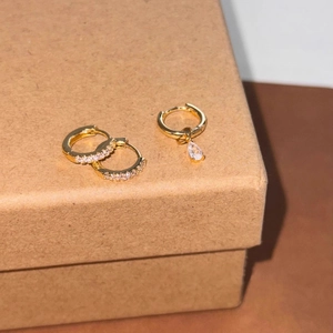 Detail of three-piece gold-plated asymmetric hoop earrings with pear-cut crystal charms