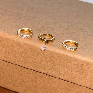 Detailed view of three-piece gold-plated earrings set with paved cubic zirconia stones
