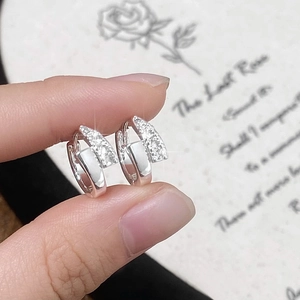 Close-up of silver earrings with layered polished surfaces and sparkling pavé crystals