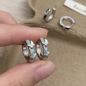 Elegant silver butterfly hoop earrings with light blue enamel inlay held by hand