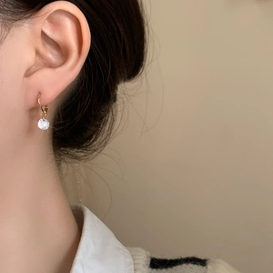 Detail of vintage gold-plated hoop earring with sparkling round zircon on a model