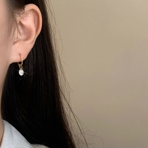 Detail of French vintage gold-plated round earrings with sparkling zircon crystals on ears