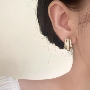 Drei-lagige goldene Creolen mit Zirkonia und Emaille, getragen von einem Modell am Ohr