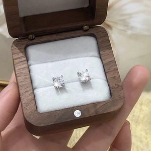 Close-up of sparkling four-prong AAA zircon earrings in a premium wooden jewelry box