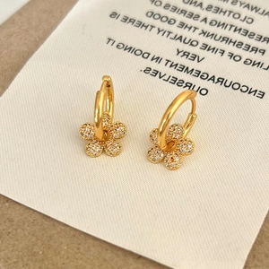 Close-up of golden flower hoop earrings with sparkling cubic zirconia pavé petals