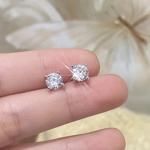 Classic four-prong cubic zirconia stud earrings held by hand to show actual size