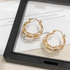 Detailed macro shot of twisted golden hoop earrings with micro-pave cubic zirconia inlay