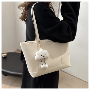 Detail of cream tote bag with TidalDryness Paris tag and plush cloud charm on shoulder