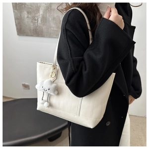 Detail of white embossed tote bag with unique wood grain texture and plush cloud charm