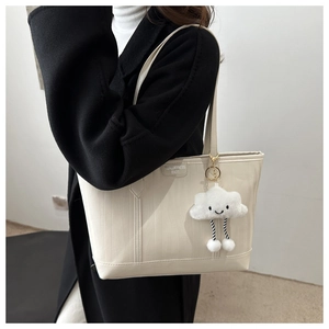 Detail of creamy white tote bag featuring a cute cloud charm and embossed texture leather