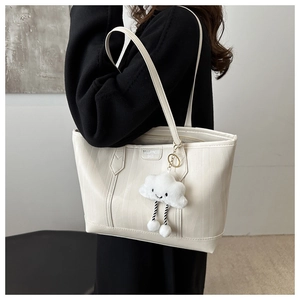 Detail of off-white tote bag with wave texture, leather label and cloud plush charm