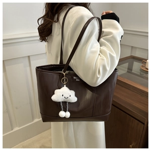 Detail of dark brown striped tote bag with cute cloud charm and plush decoration